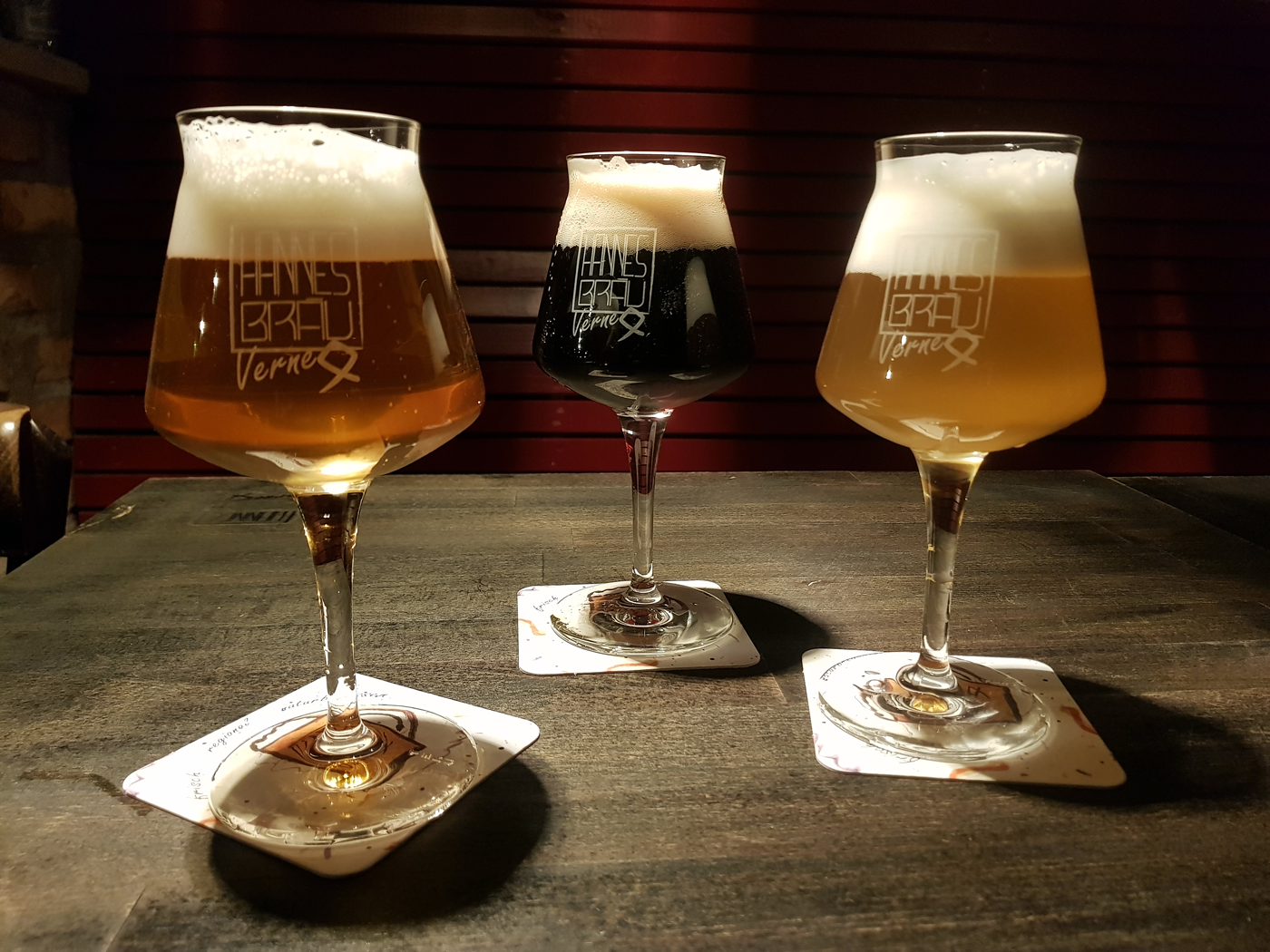 Drei Gläser HannesBräu: e hell, e dunkel unn e trieb Bier uff'm Holzdisch